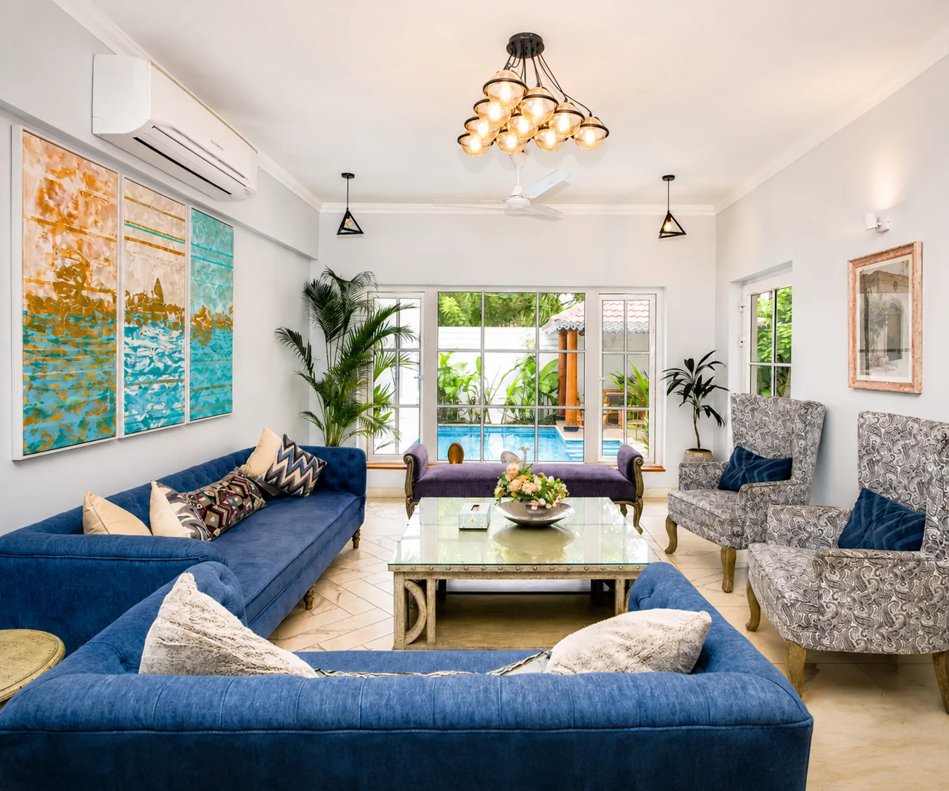 Living room with blue sofas, opening onto the pool